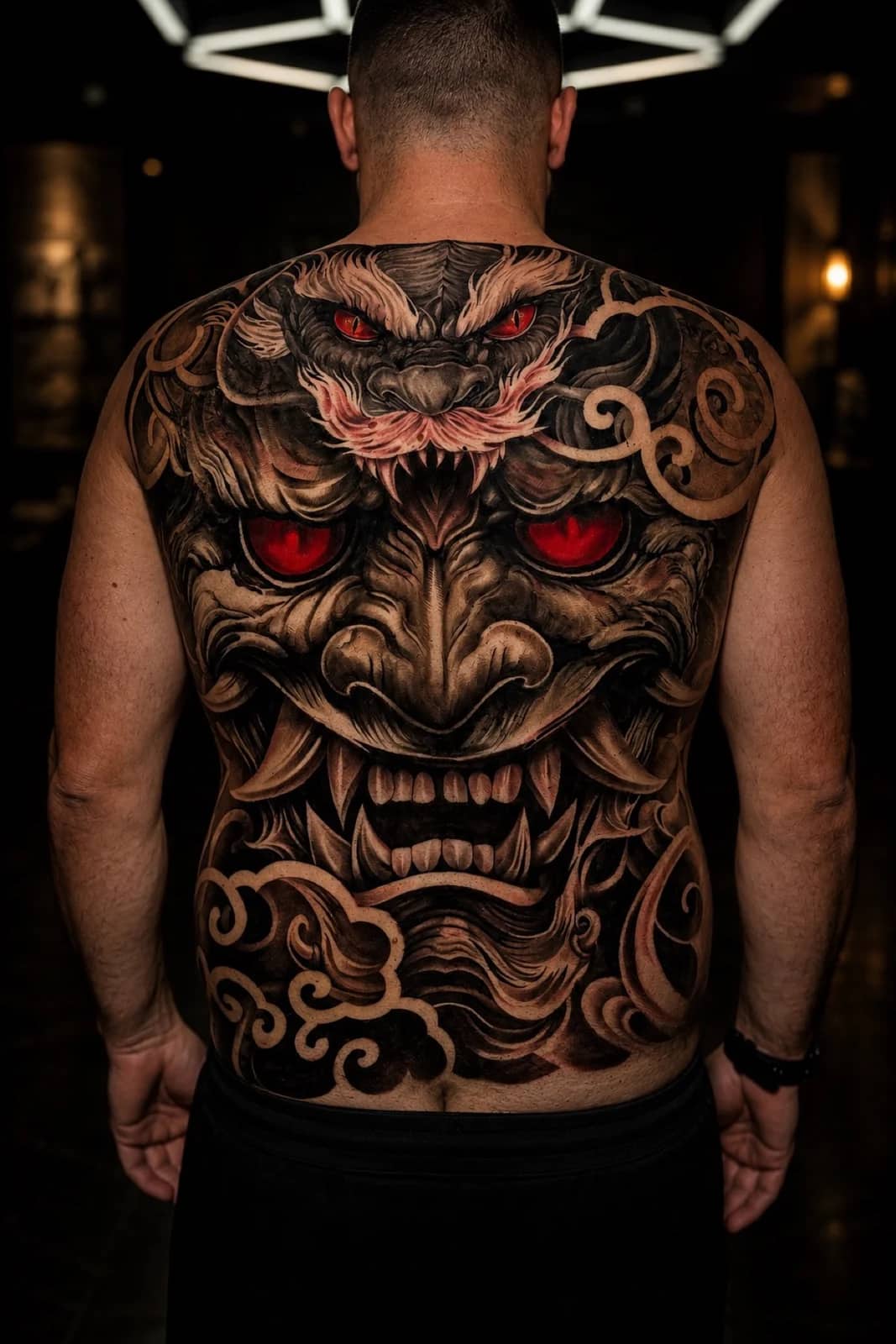 Japanese full-back oni or Hannya tattoo with glowing red eyes and cloud swirls at Bloodline Tattoo Bangkok